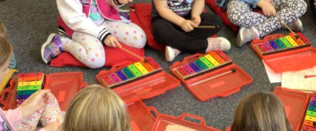 A close up photo of young children playing glockenspiels