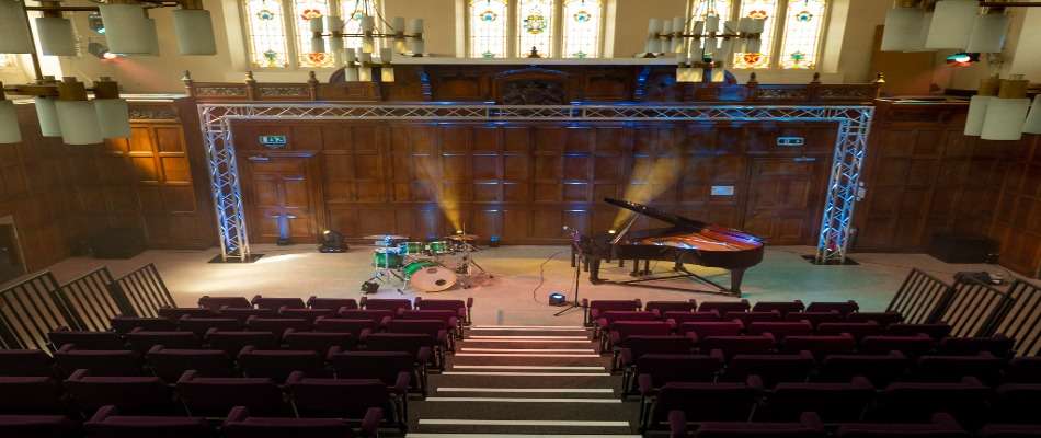 Photo of the Calderdale Music performance space with a drum kit and grand piano in front of rows of seats